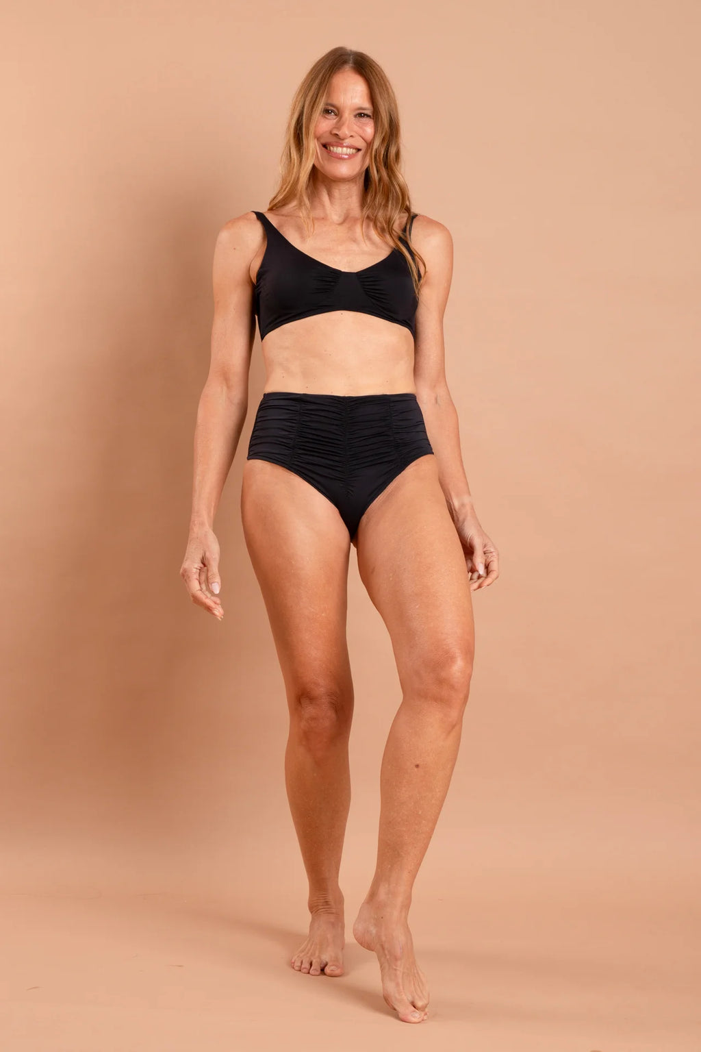 Fotografia de biquíni Aurora liso na cor preta, hot pants drapeada de cintura alta, top contínuo modelo camiseta com nó decorativo central, marca Isa Rodrigues Resortwear. Frente