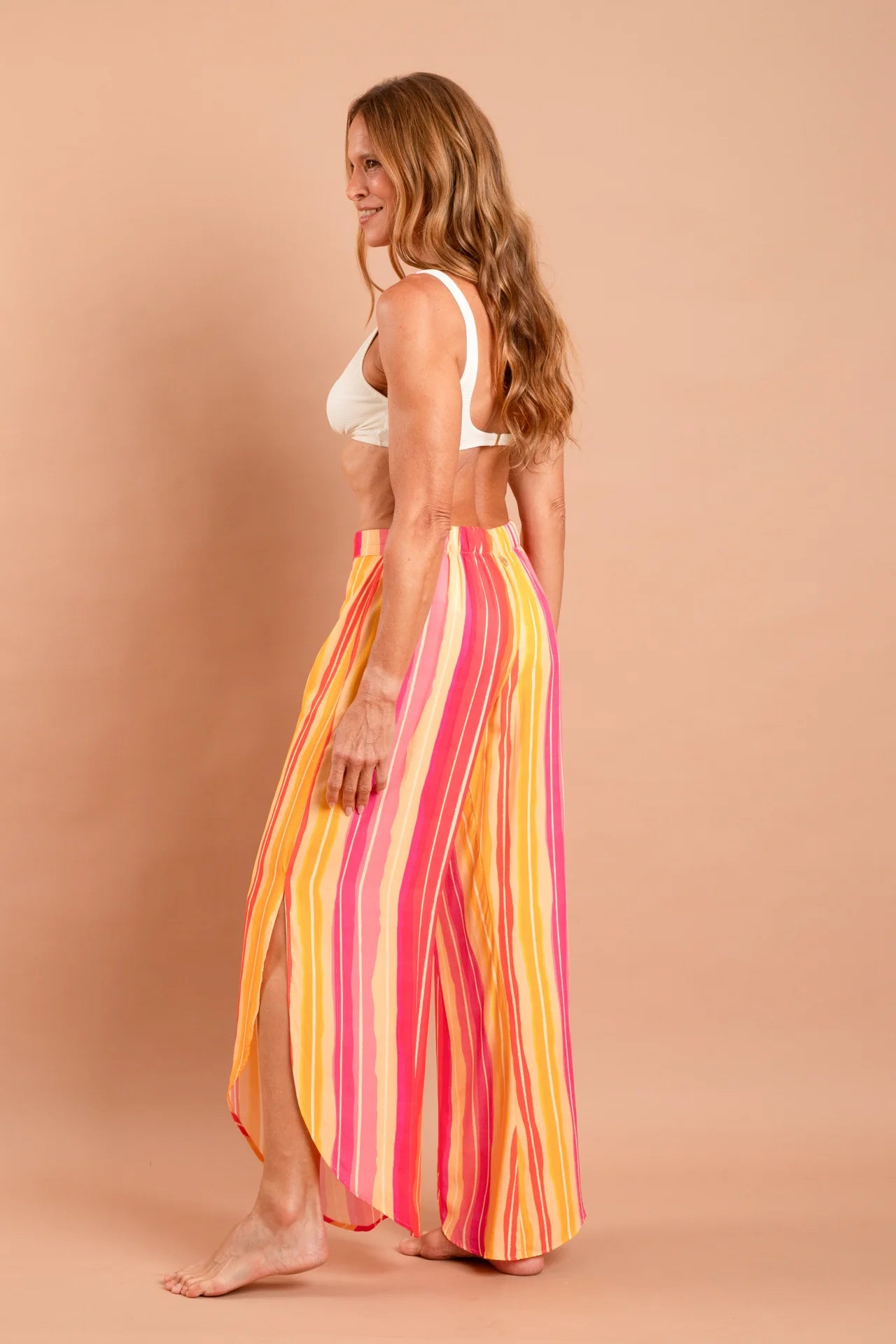 Fotografia de calça feminina ampla com padronagem autoral Estampa Solar, modelagem easy chic com cós liso e fluidez nas pernas, marca Isa Rodrigues Resortwear. Foto lado