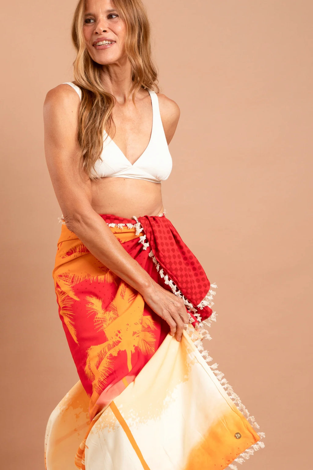 Fotografia de canga de praia modelo Poente na cor quente laranja avermelhado, estendida revelando proporções quadradas de 1,40m e fibra de viscose, marca Isa Rodrigues Resortwear.